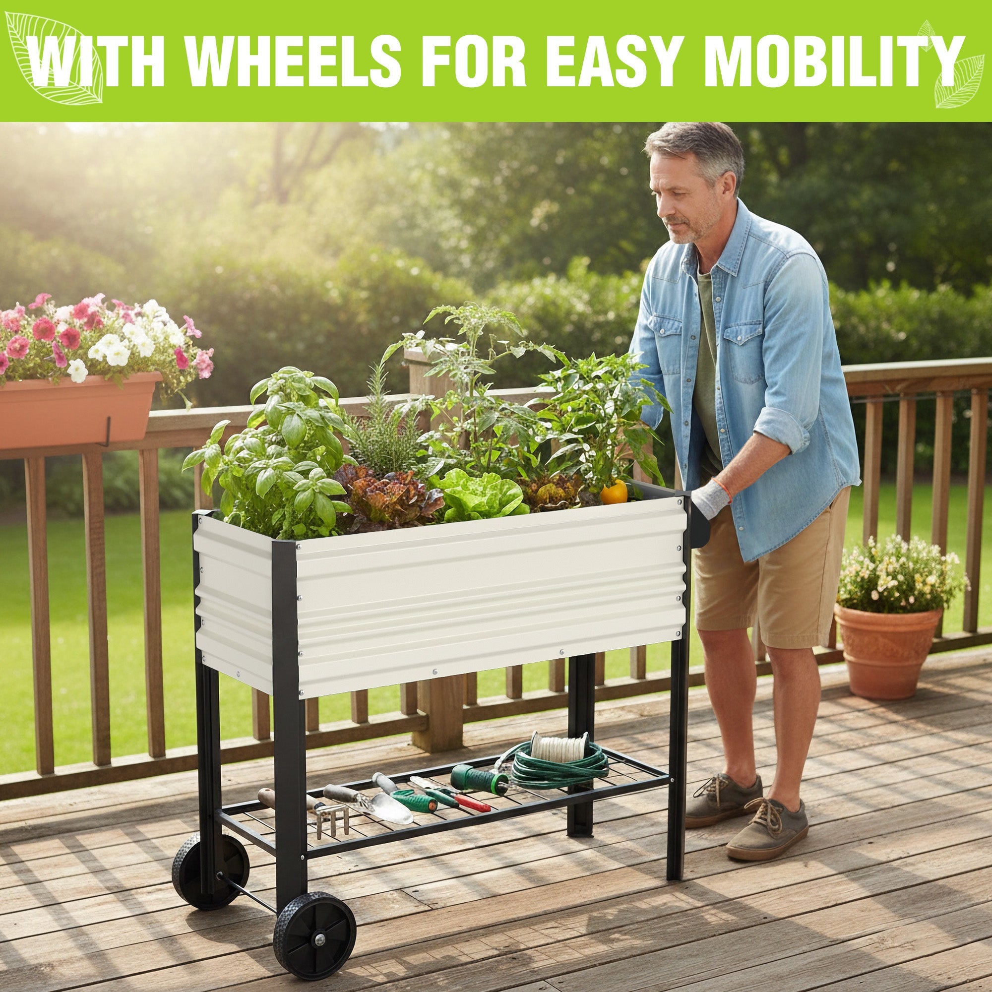 White raised garden bed with wheels on a patio, filled with plants and tools.