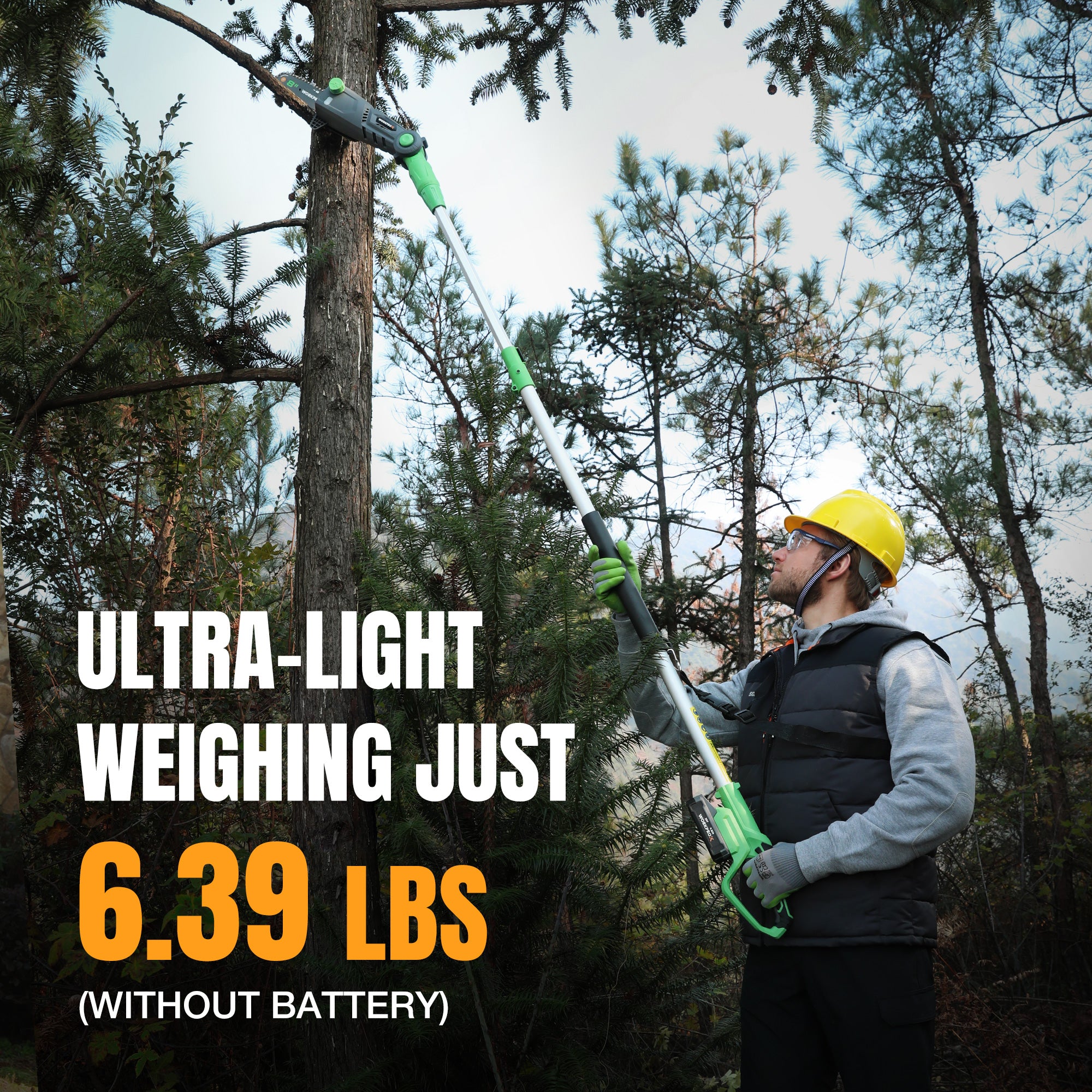 Person using a green cordless pole saw on a long extension pole in a tree area