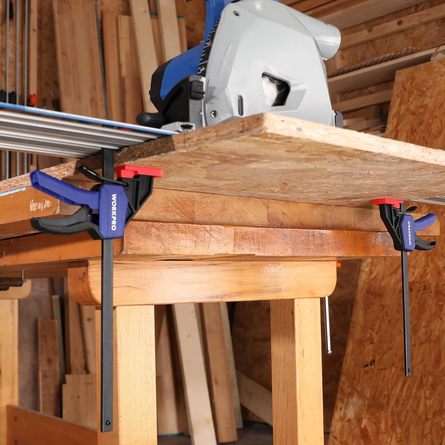Track saw clamps attaching a guide rail on top of lumber on a workbench.