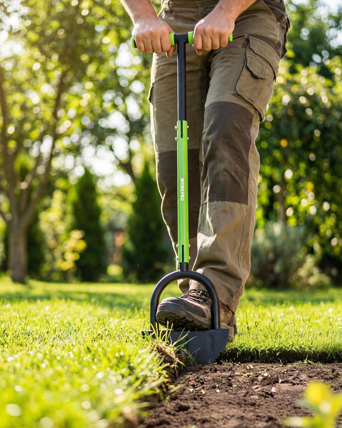 Manual lawn edger in use, green handle with black U-frame blade cutting soil