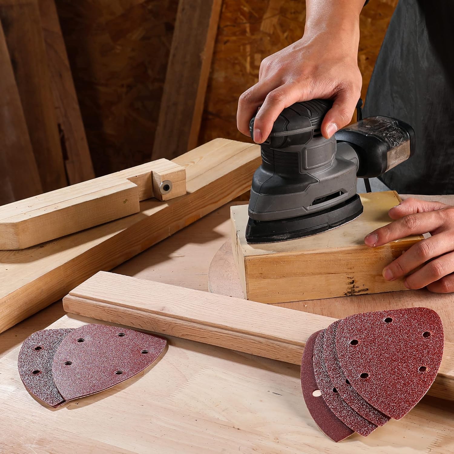 Red triangular sanding pads with hook-and-loop backing, shown on wood during sanding