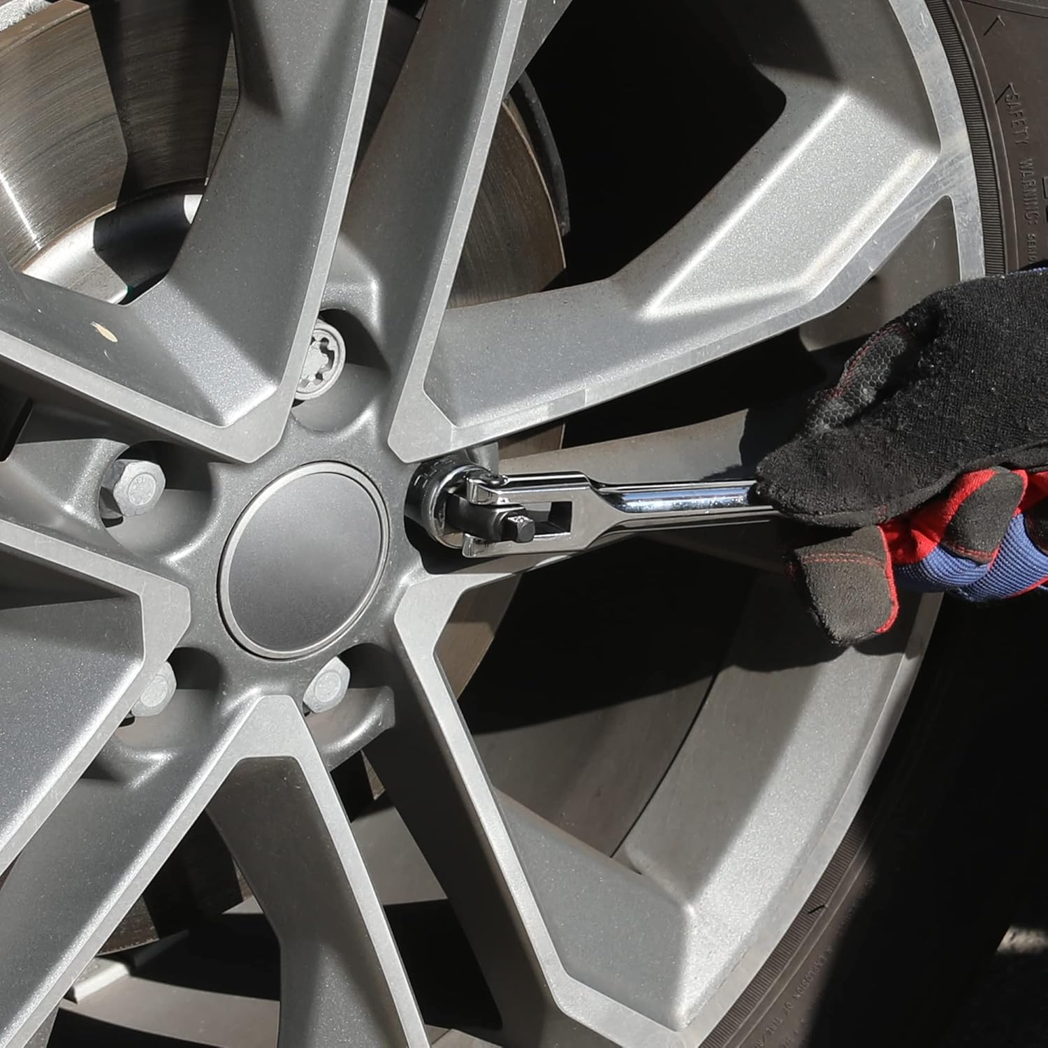 Breaker bar used on car wheel lug nut area with gloved hand