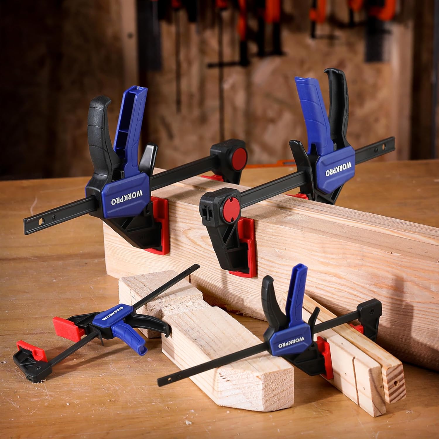 Multiple bar clamps securing a wood workpiece; black jaws, red pads, blue handles