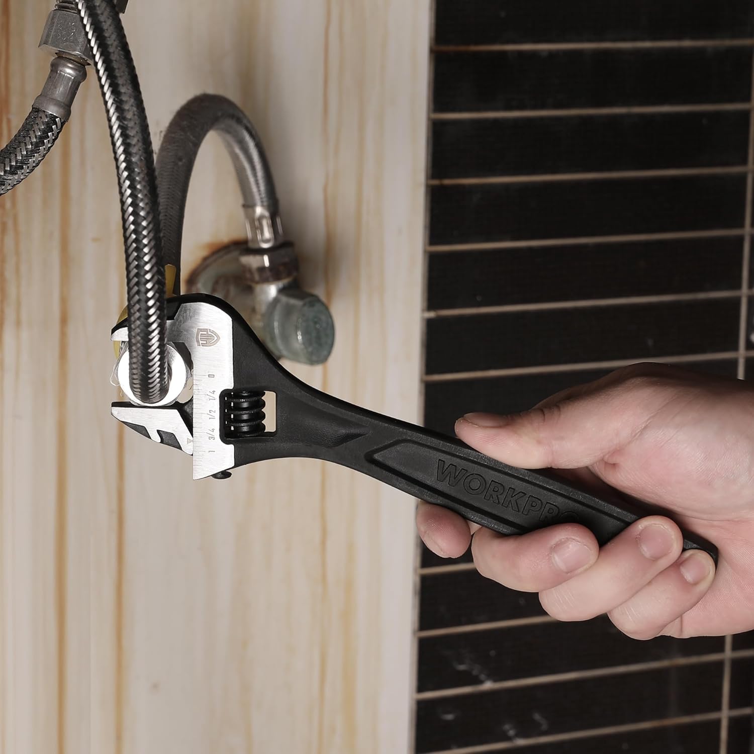 Black adjustable wrench in hand tightening a plumbing metal fitting