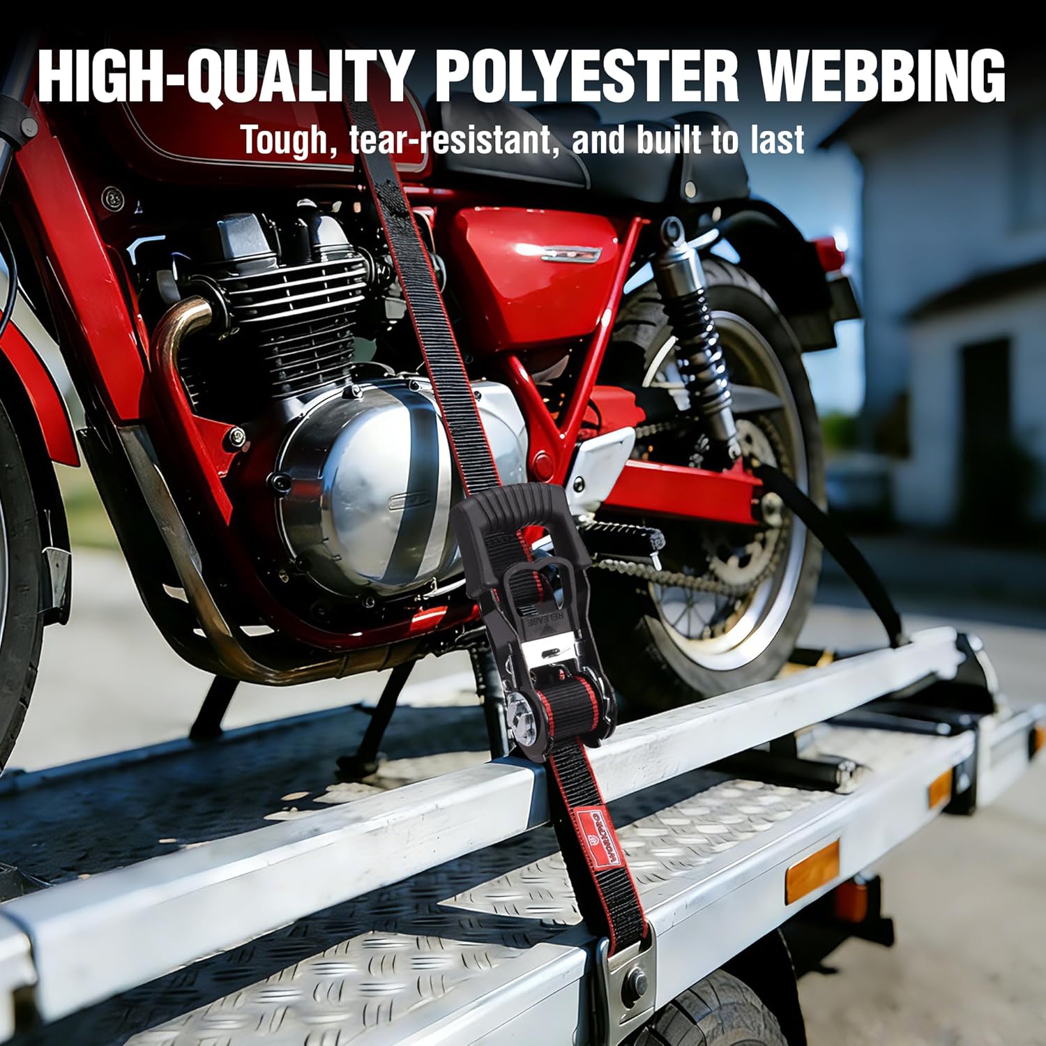 Red-and-black ratchet tie-down strap securing a motorcycle on a metal platform