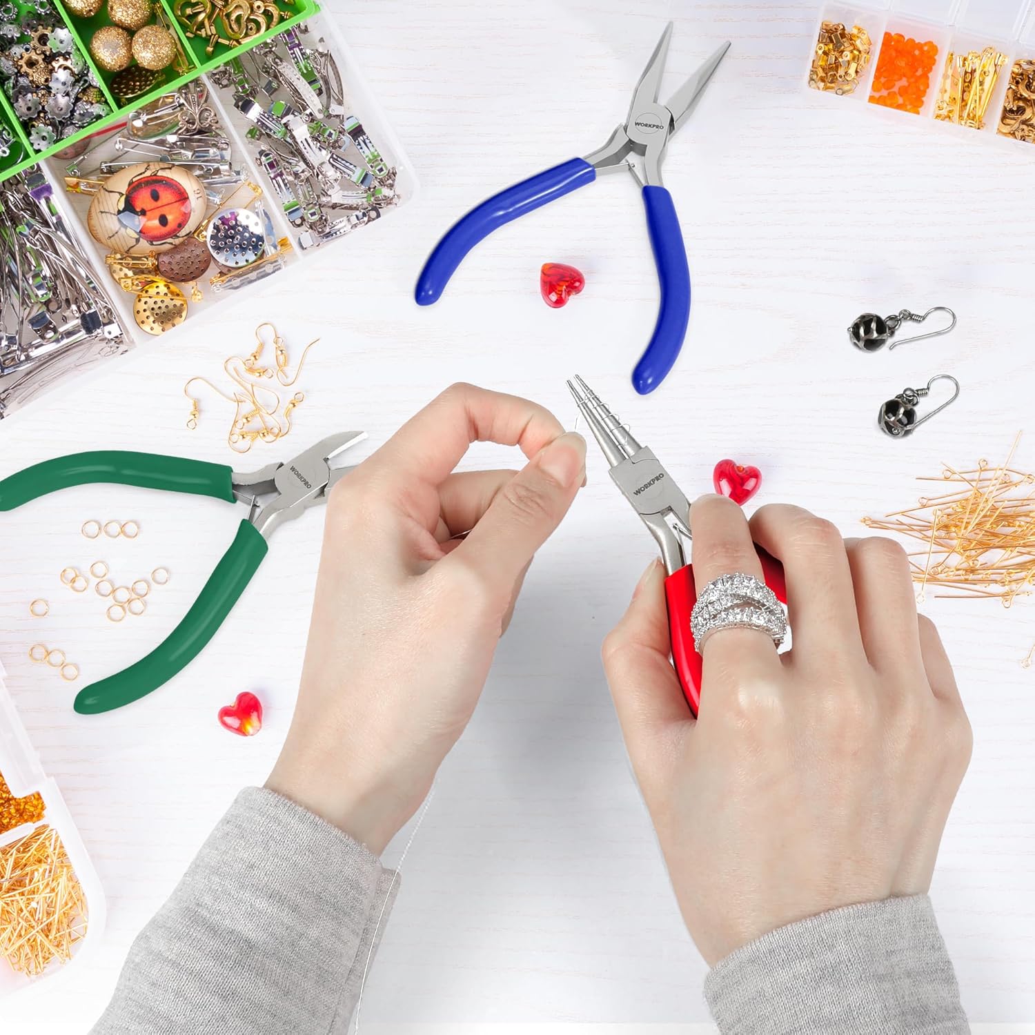 Jewelry pliers set on crafting table with hands using red-handled and blue-handled pliers