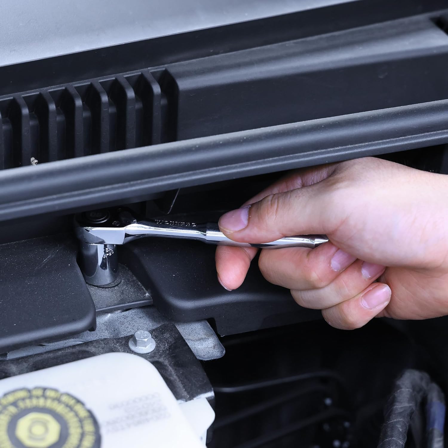 1/4 in ratchet wrench being used in an engine bay, chrome head on socket.