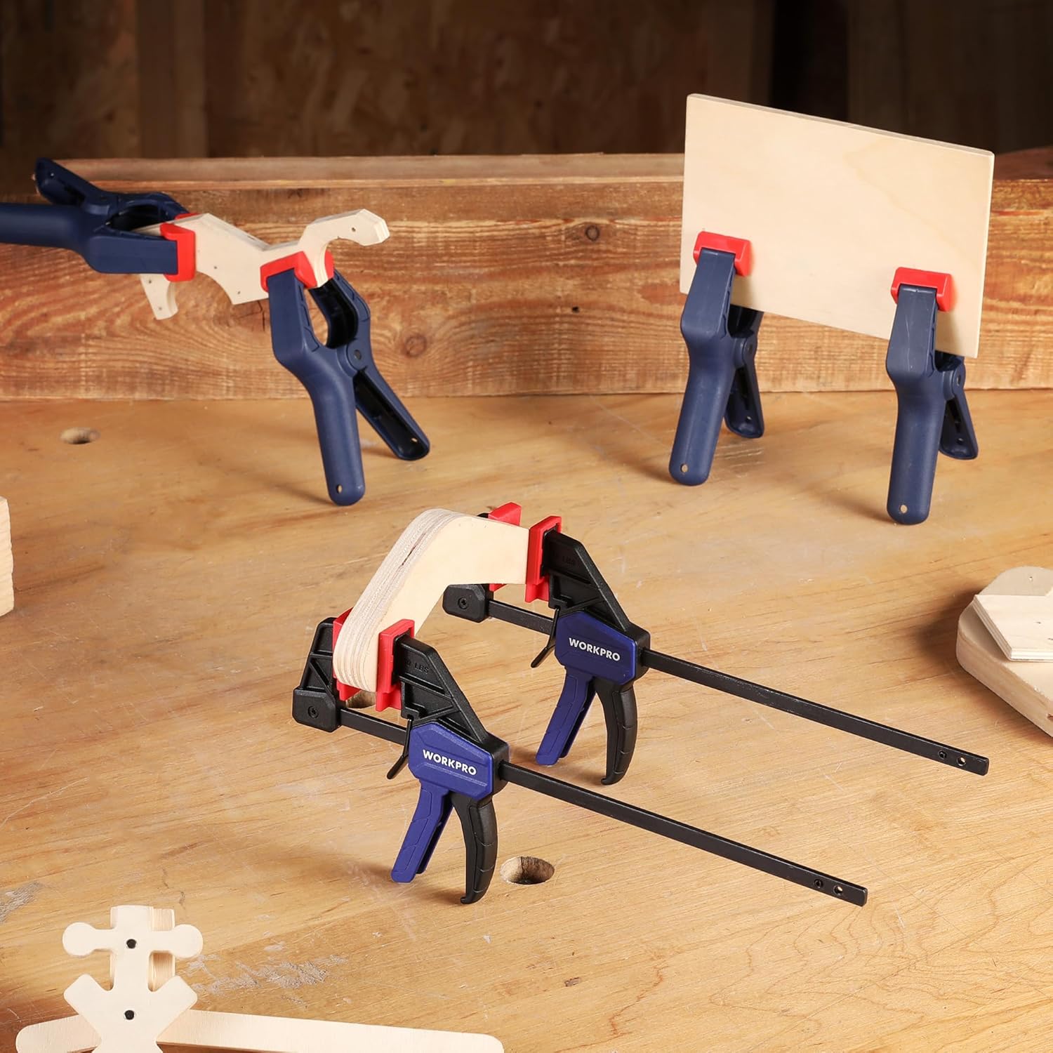 Bar clamps on a wooden panel; black clamp bodies with red pads and blue handles