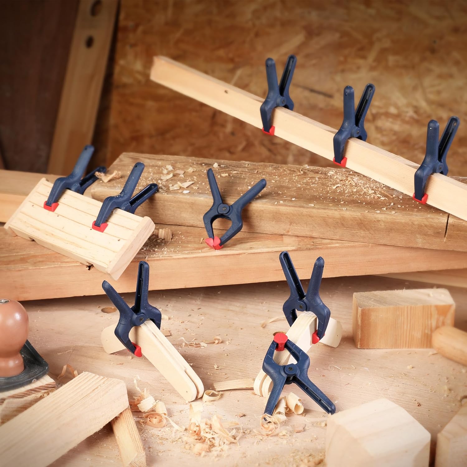 Multiple dark blue spring clamps with red pads securing stacked wood pieces