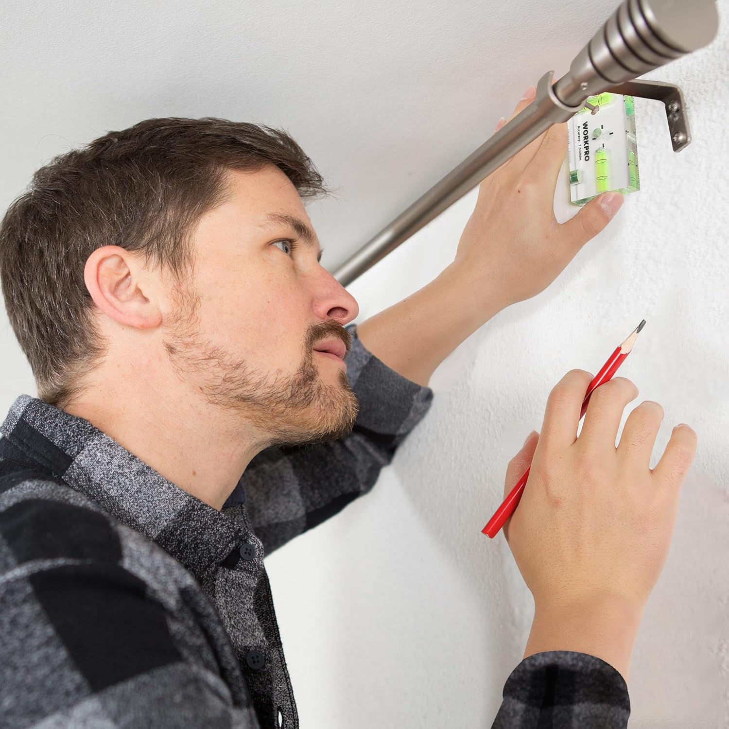 Magnetic pocket level with green vials held to a wall for picture hanging leveling