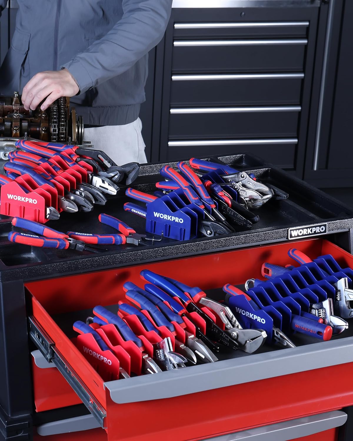 Red and blue tool organizer racks in a drawer holding hand tools in slots