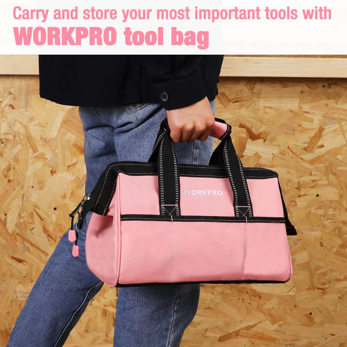 Pink tool bag with black handles and front zip, carried by a person in workwear.