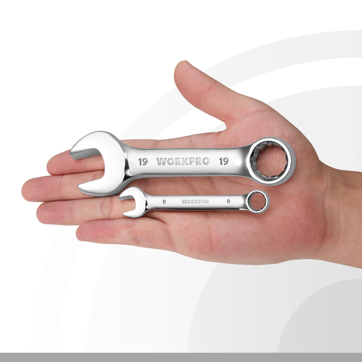 Two stubby combination wrenches with chrome finish held in a hand, sizes visible