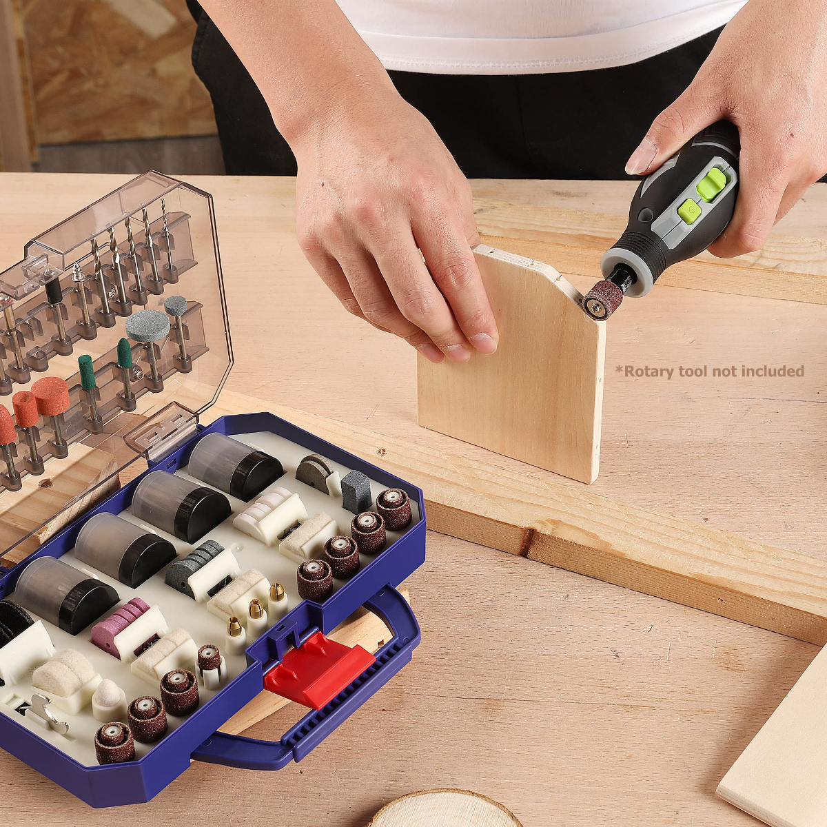 Rotary tool accessory kit open on bench as a person sands a wooden board
