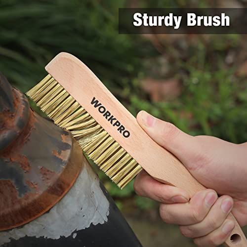 Wood-handled brass wire brush with golden bristles held against rusted metal