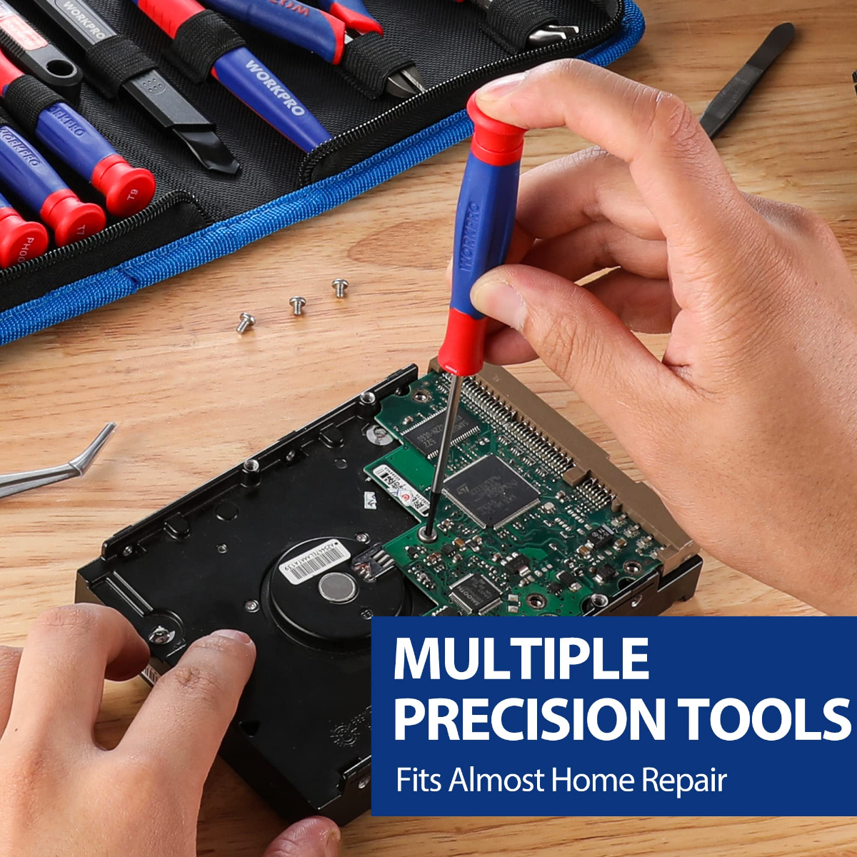 Blue-handled precision tool held over open electronics with small screws on wood surface
