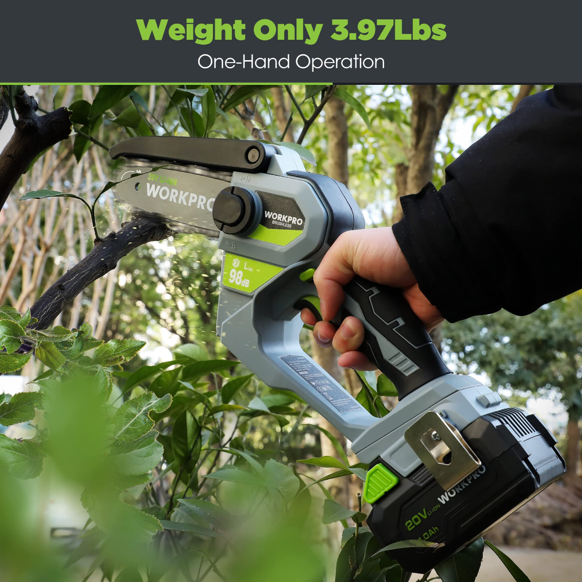 Hand holding compact cordless chainsaw outdoors with battery pack attached