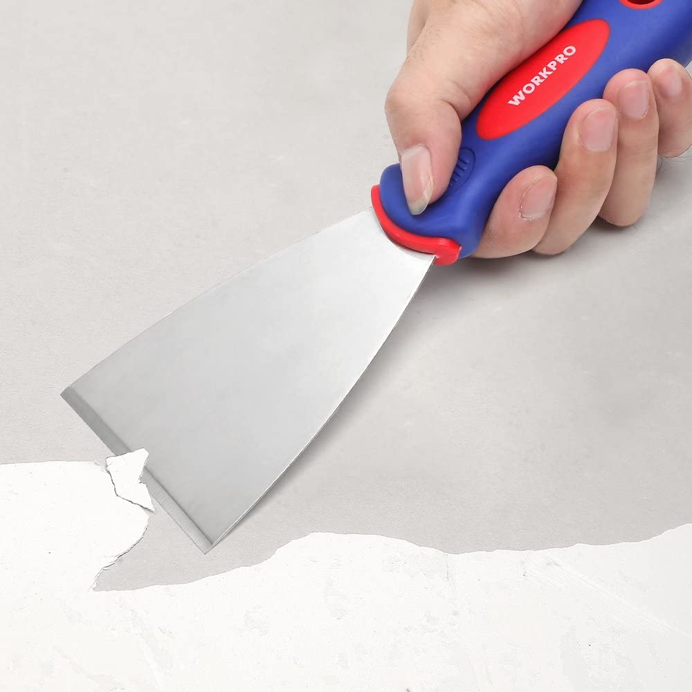 Hand using a blue-handled stainless steel putty knife to spread compound