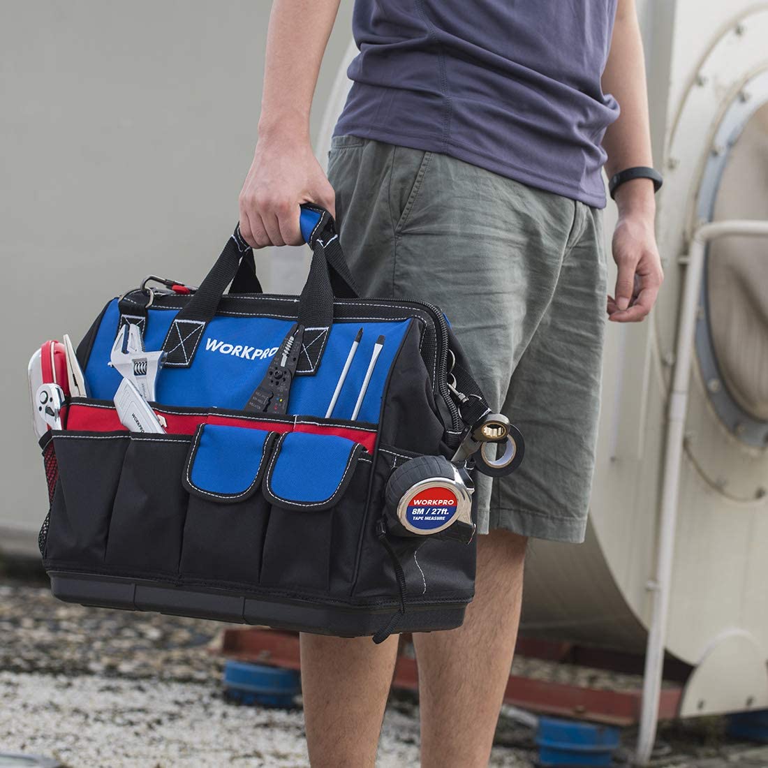Tool bag carried by person, showing adjustable shoulder strap and front organizer pockets