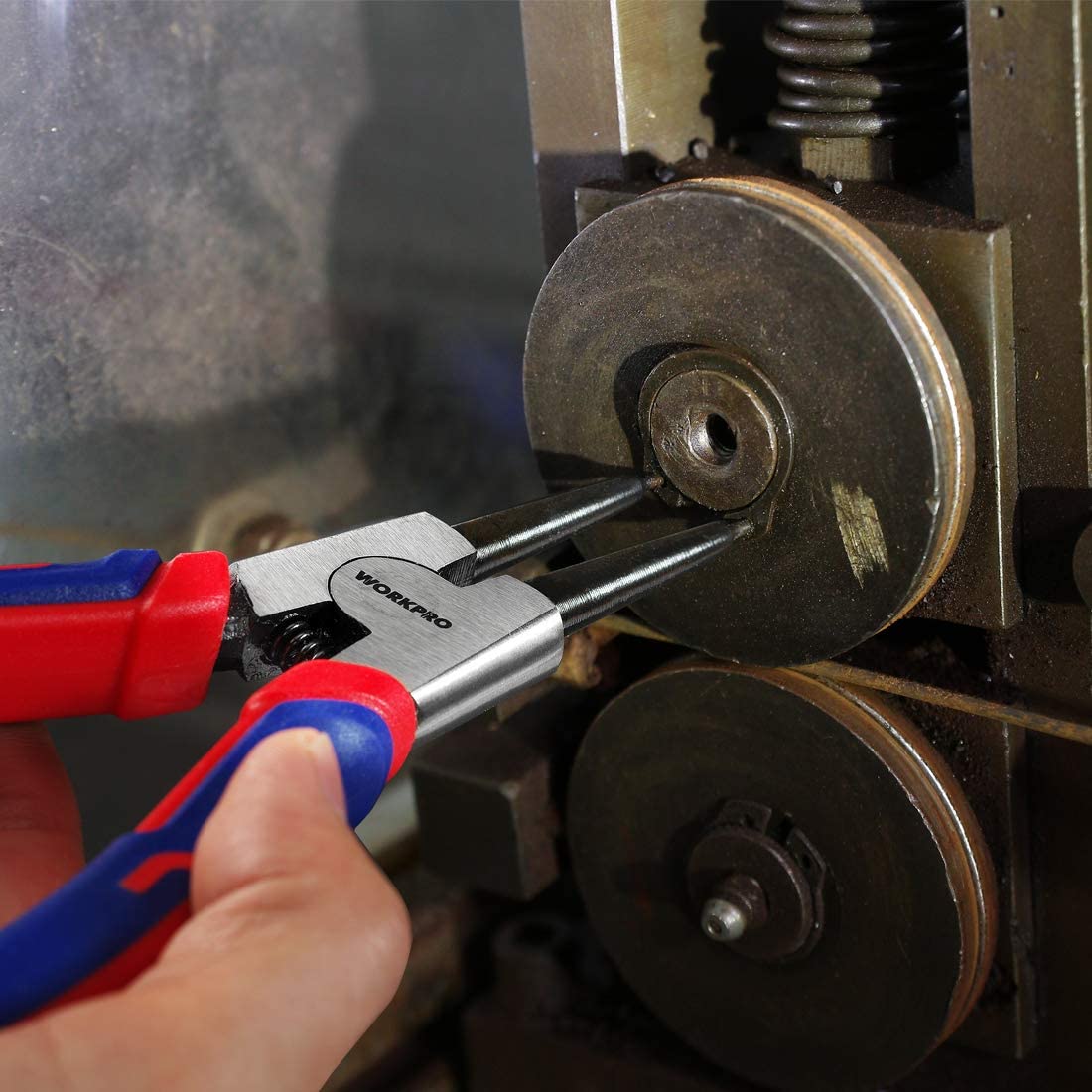 Snap ring plier tool in use on metal shaft, blue/red handle, black jaws