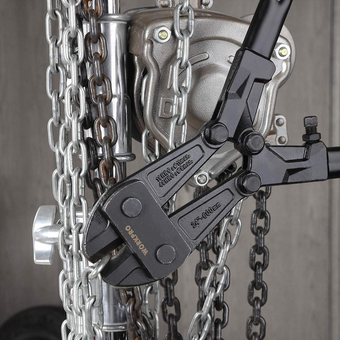 Bolt cutter clamp gripping metal chains on a gate fence