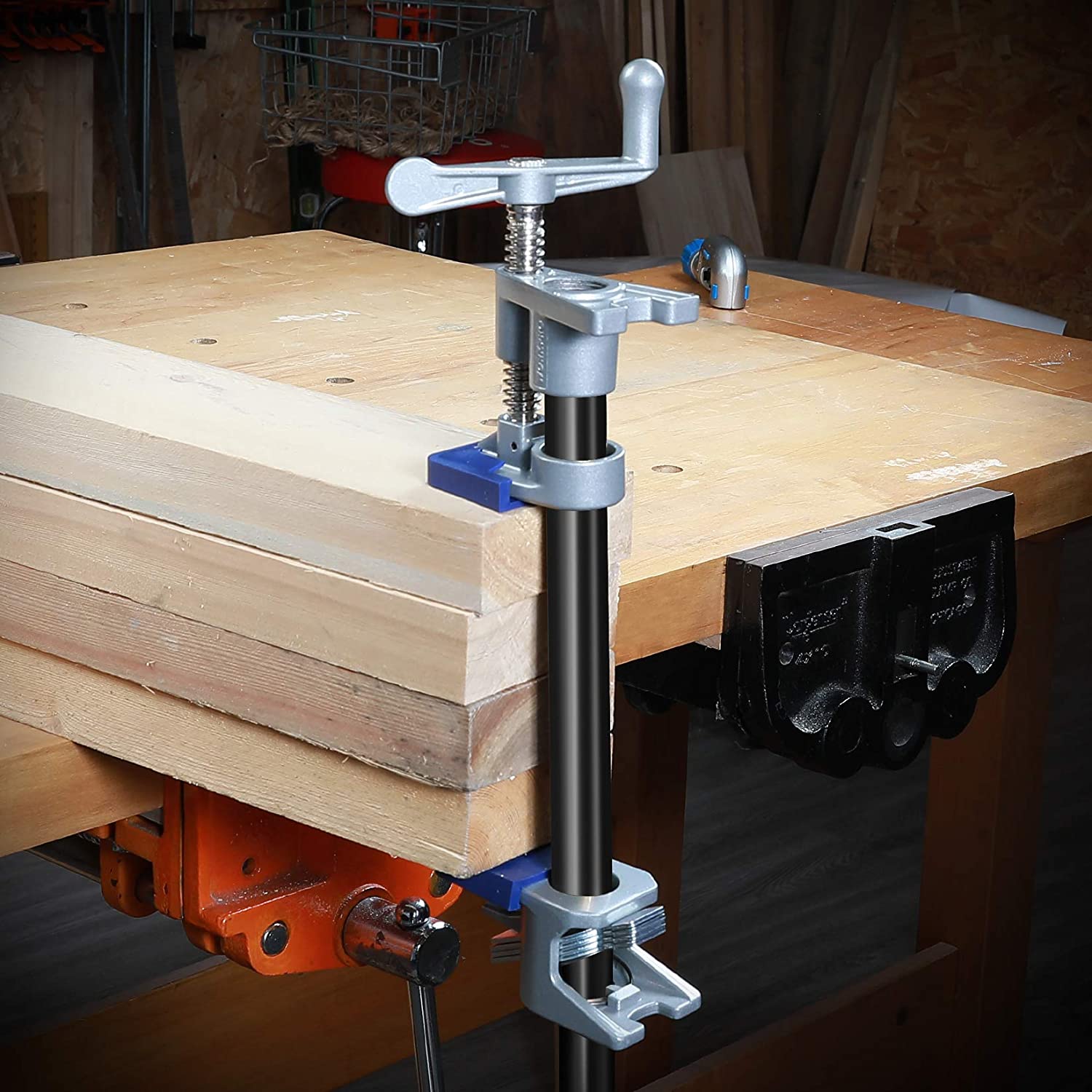 Pipe clamp securing a black pipe to a workbench top with a silver handle and base