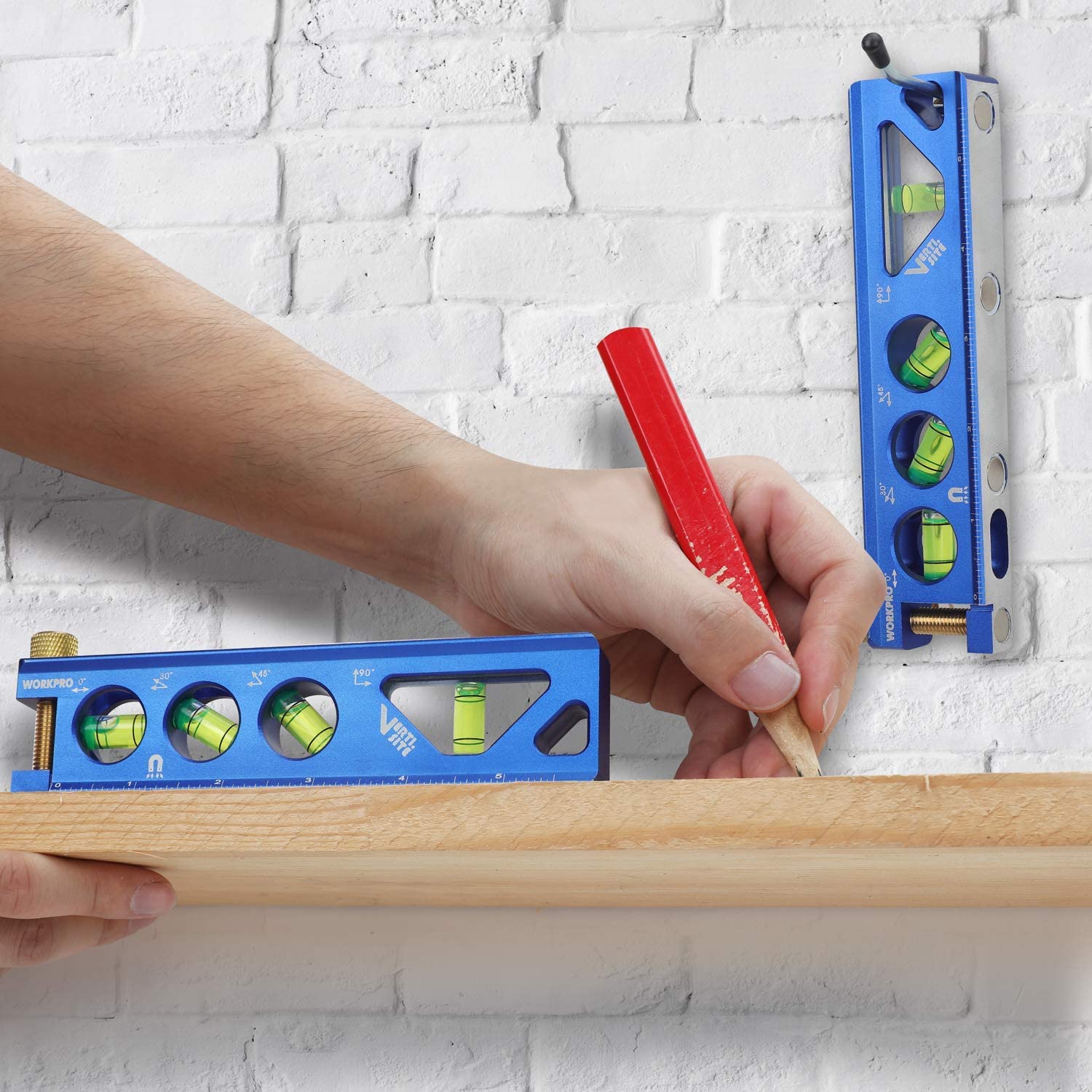 Hand using a blue torpedo level with green vials to mark a wall board