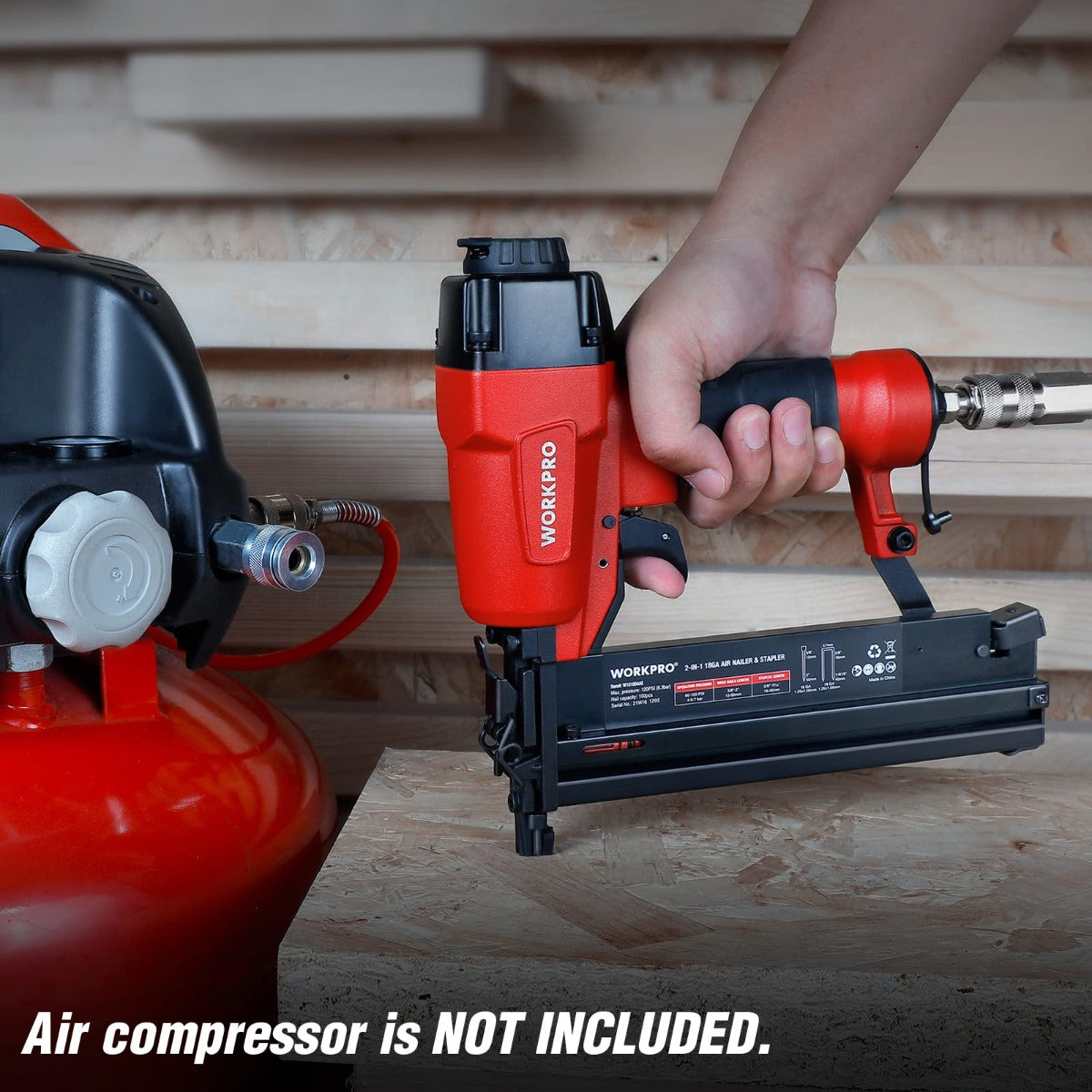 Red and black pneumatic nailer driving fasteners into wood with air hose connection