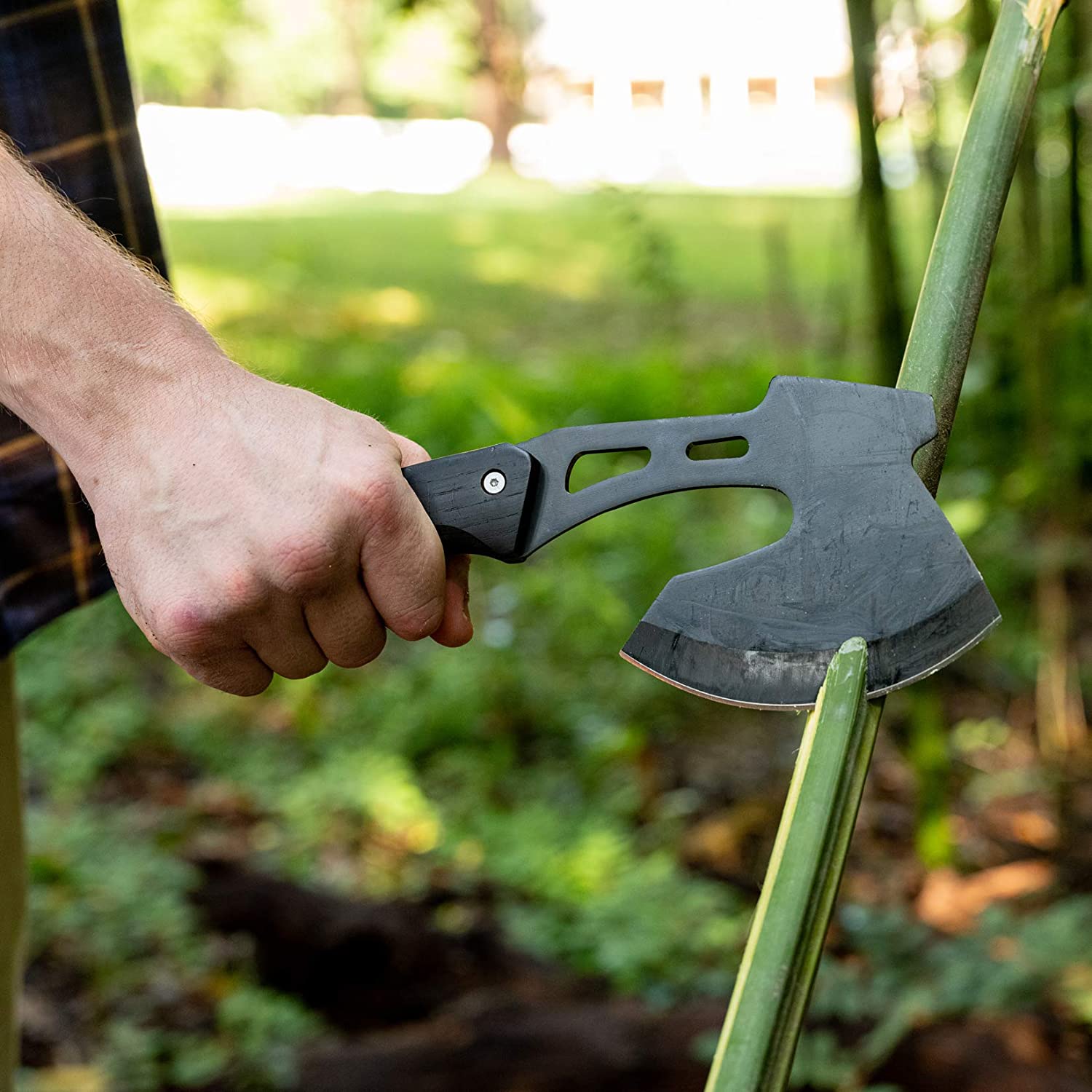 Black-head axe with wooden handle held outdoors near stacked logs