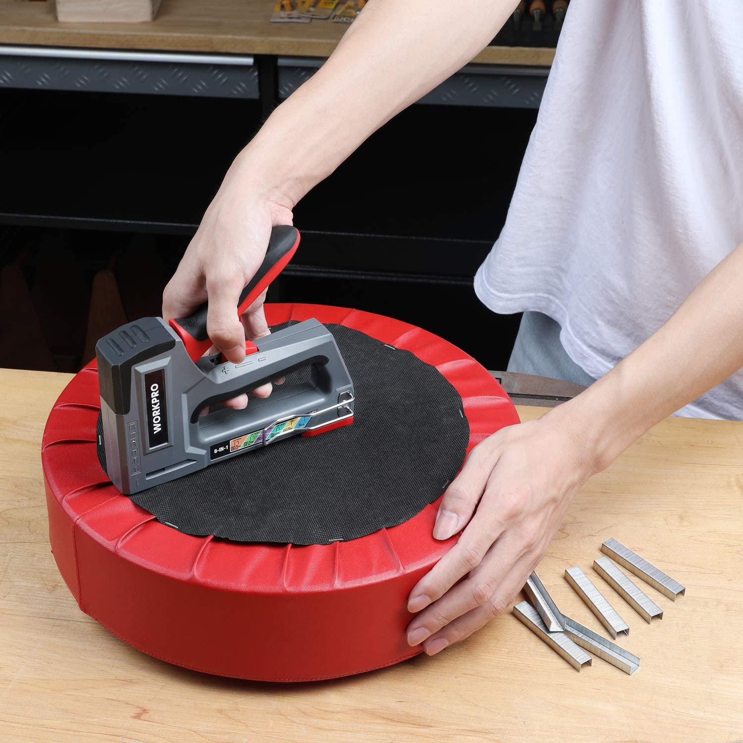 Hands using a stapler, with loose metal staples and brad nails