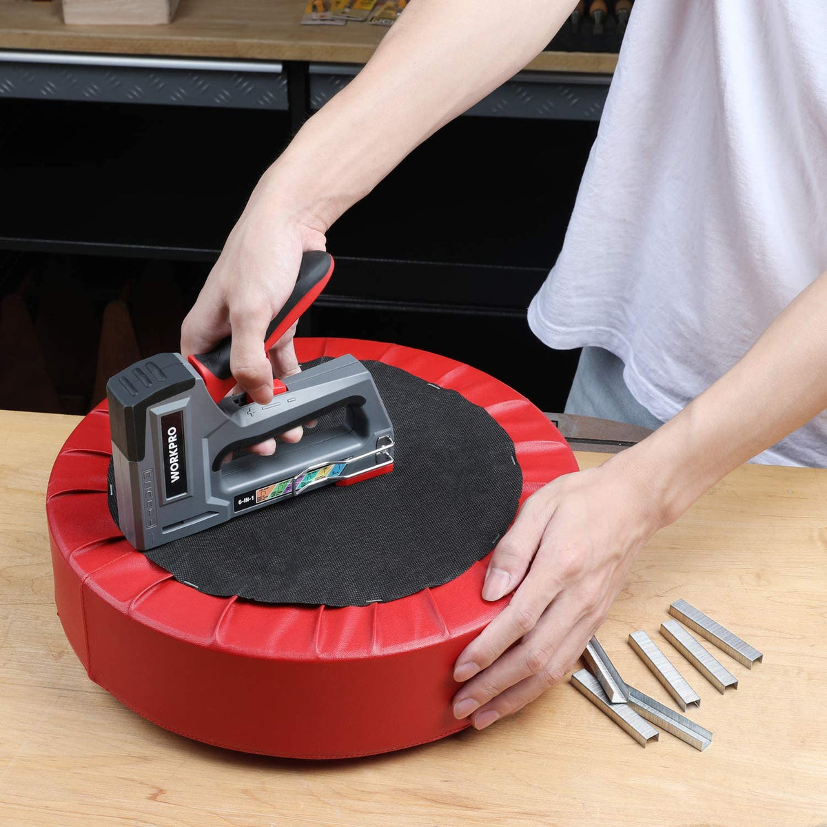 Hands using a stapler, with loose metal staples and brad nails