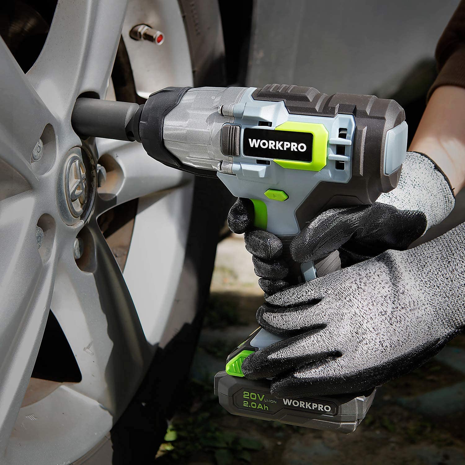 Cordless impact wrench in gloved hands tightening a wheel bolt on a vehicle