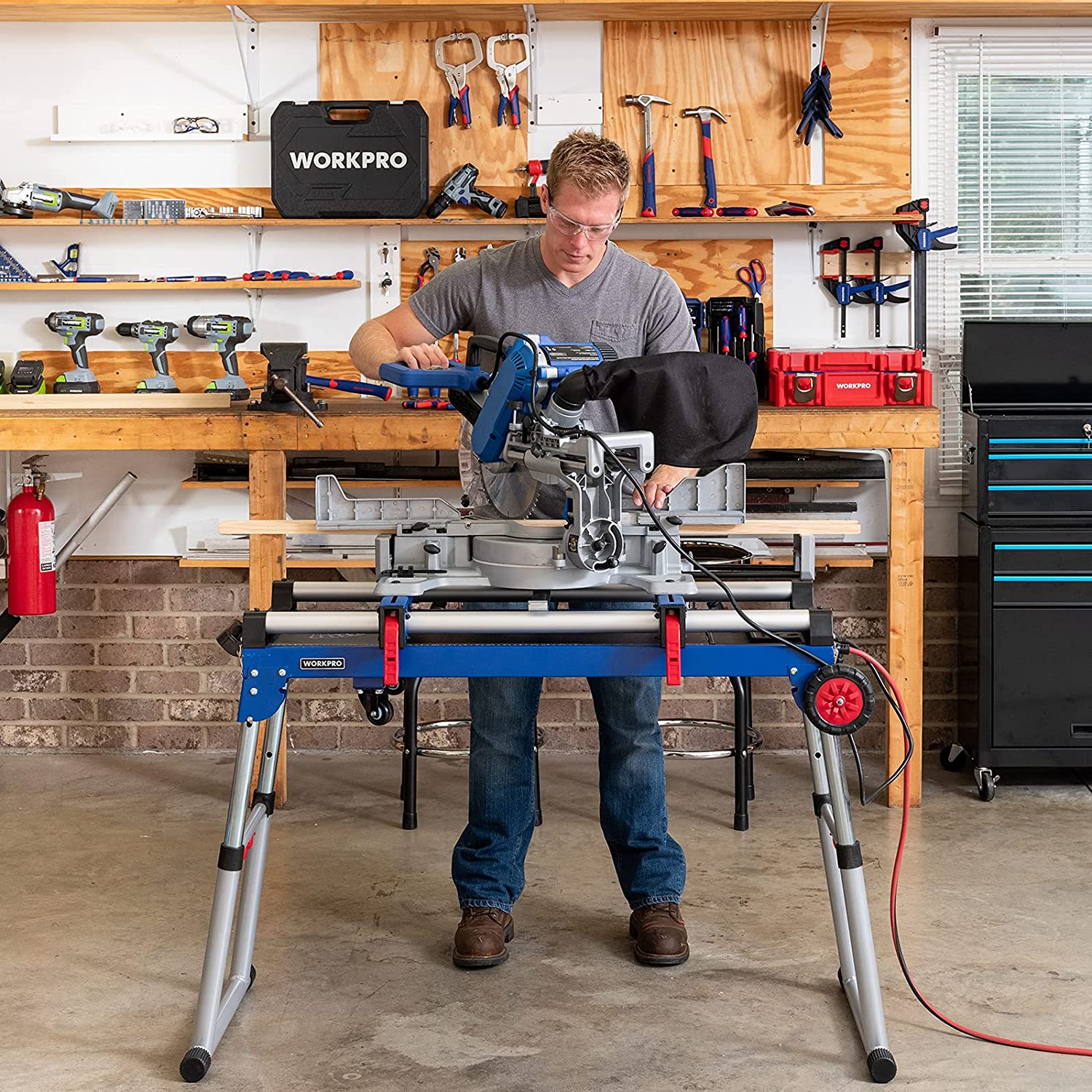 Blue miter saw stand workbench with height-adjustable legs in a workshop