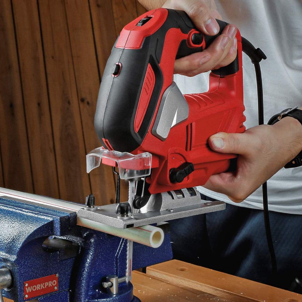 Red and black jigsaw cutting wood with visible T-shank blade