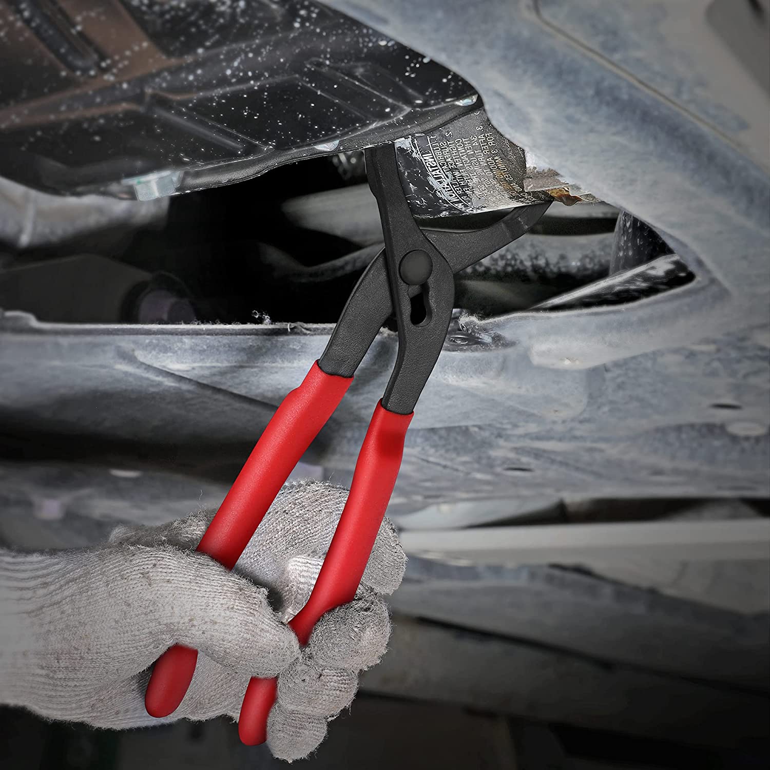 Oil filter pliers clamped to an engine oil filter area with red handles