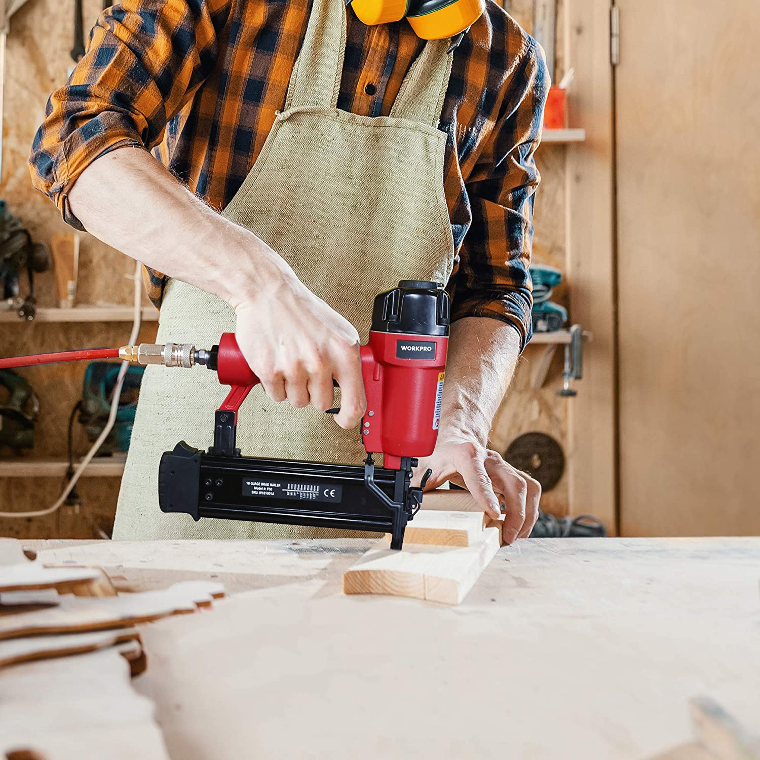 Pneumatic brad nailer fastening wood boards in a workshop