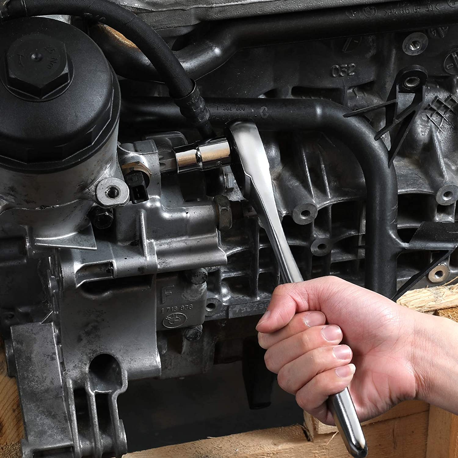 Torx socket bit engaged on machinery while held by a hand with a wrench