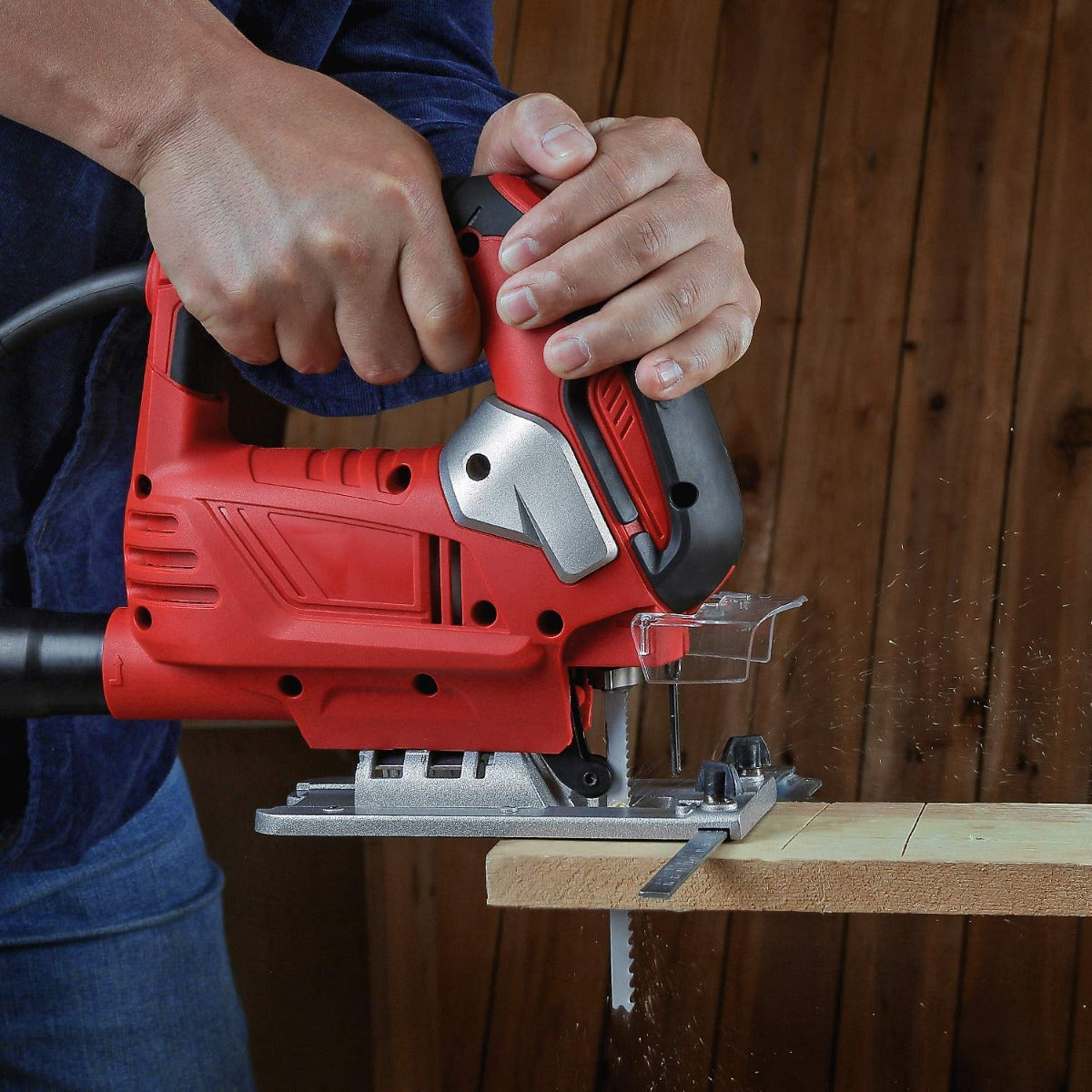 Hands operating a red jigsaw on wood, showing mounted T-shank blade