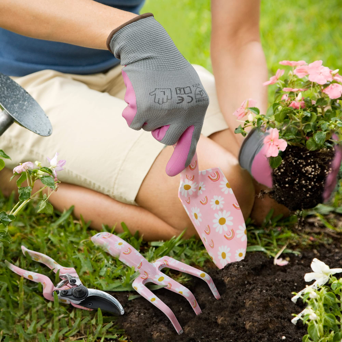 Pink floral garden tools and gloves planting a small shrub in soil