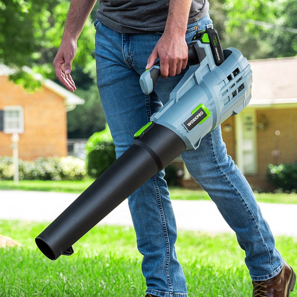 Cordless leaf blower held by handle, black tube extended for leaf clearing