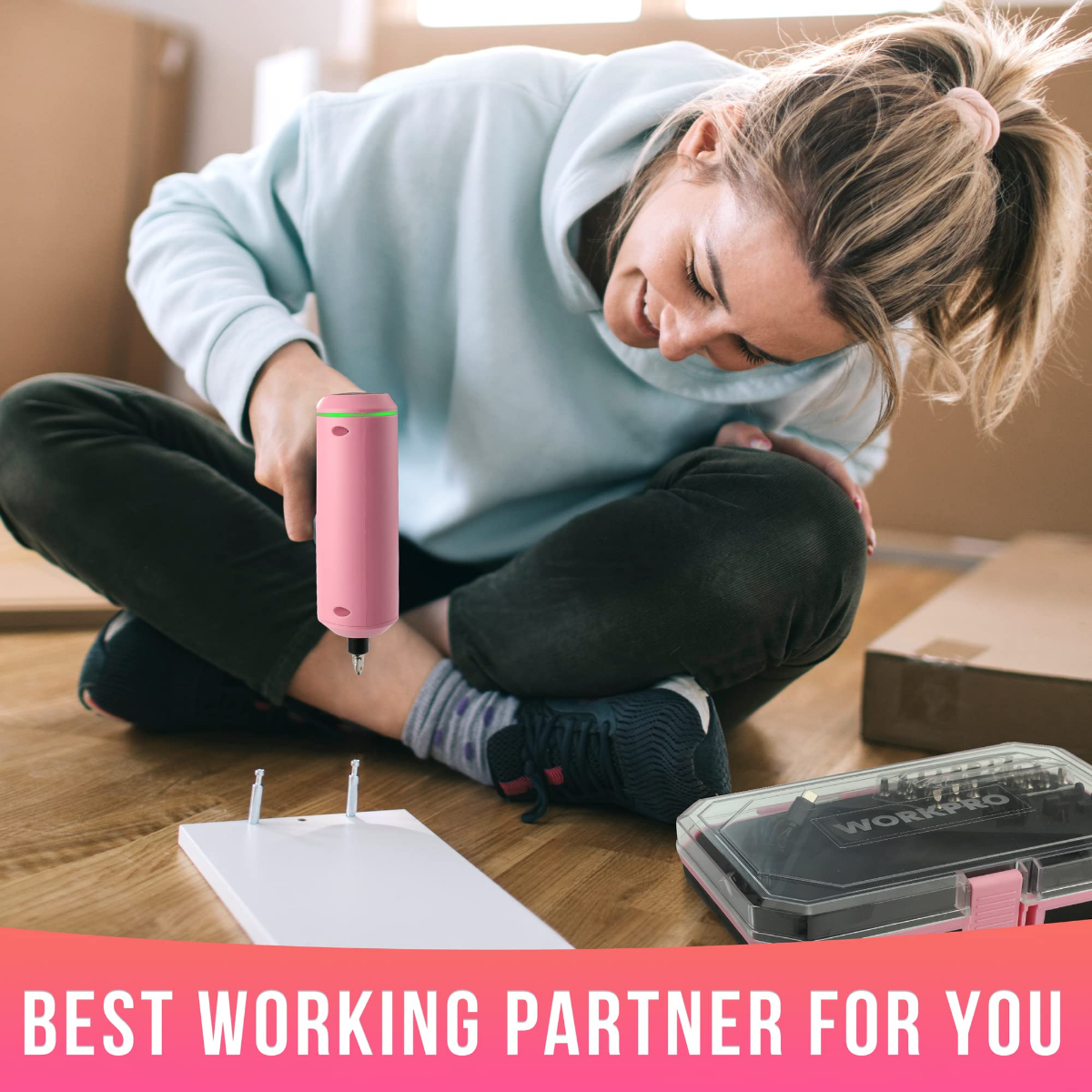 Cordless electric screwdriver, pink body in hand while assembling items on a table